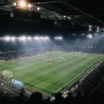 Football stadium under floodlights at night during a match