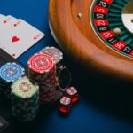 Online casino games — roulette, cards, dice and chips beside a laptop