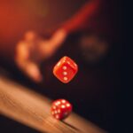 Stock photo of red dice tumbling against a blurred background, used to illustrate chance. Not a football match.