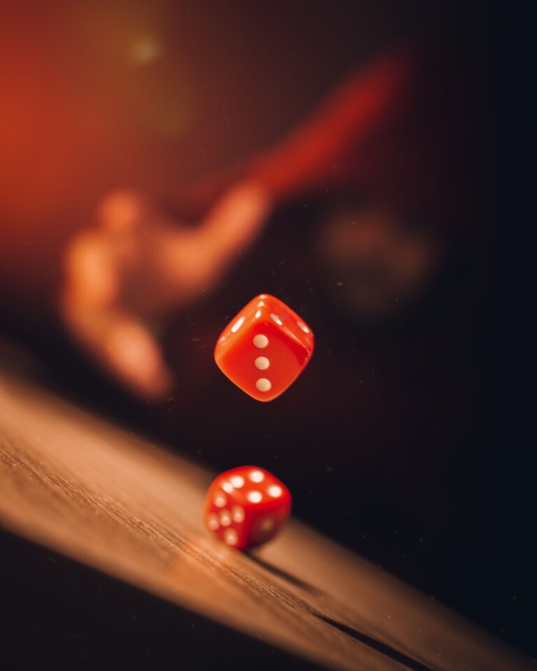 Stock photo of red dice tumbling against a blurred background, used to illustrate chance. Not a football match.