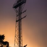 Stock photograph of a single stadium floodlight tower silhouetted against a sunset sky. It is not a photograph of the Emirates Stadium, Arsenal, Leeds United or any Premier League match.
