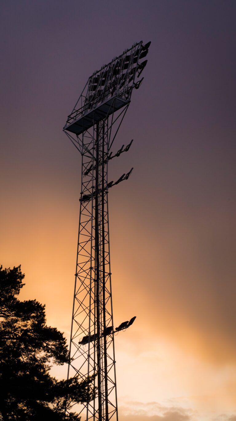 Stock photograph of a single stadium floodlight tower silhouetted against a sunset sky. It is not a photograph of the Emirates Stadium, Arsenal, Leeds United or any Premier League match.